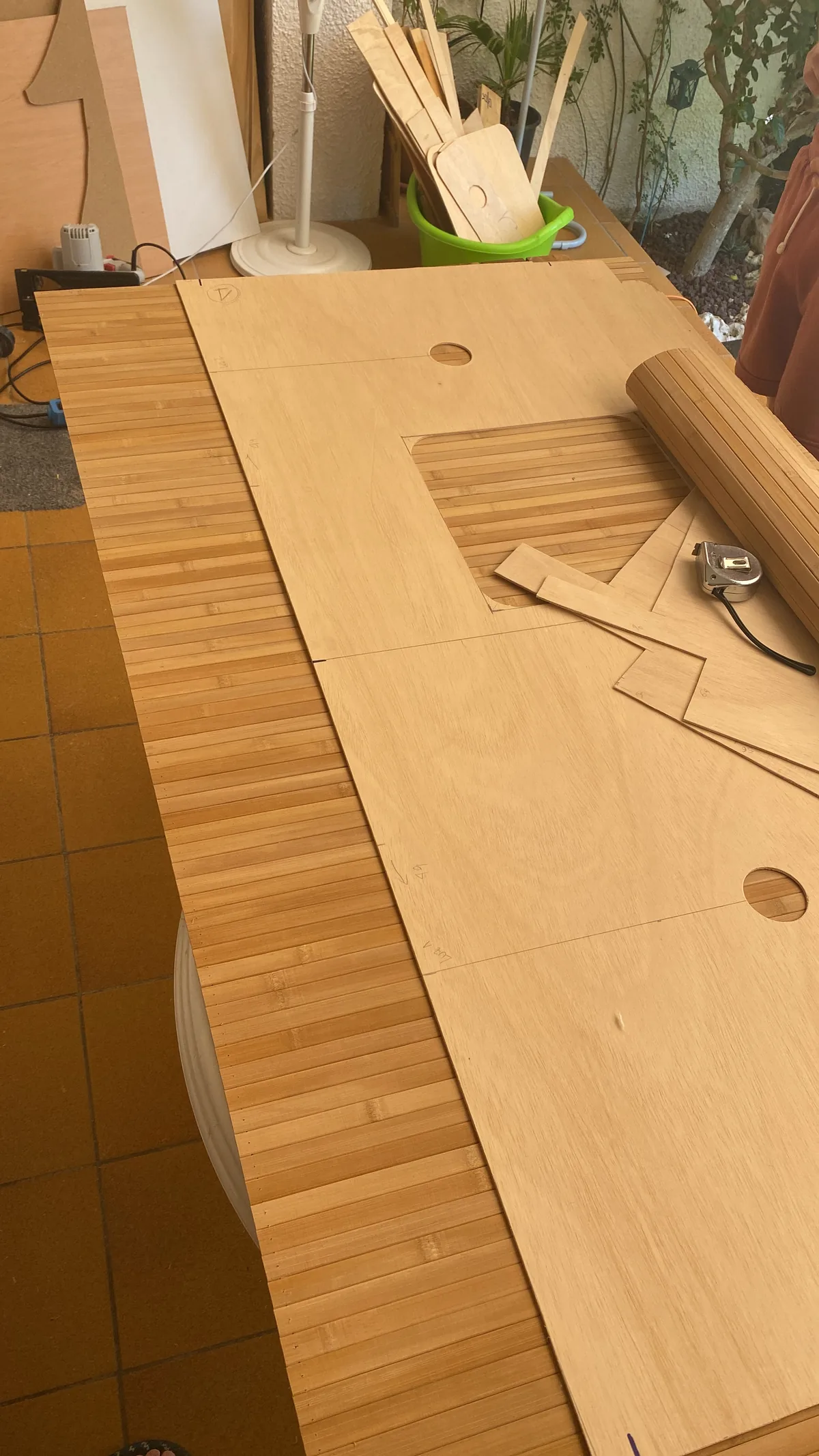 Piezas de madera contrachapada y bambú cortadas a medida para el mobiliario de una furgoneta camper, con cinta métrica