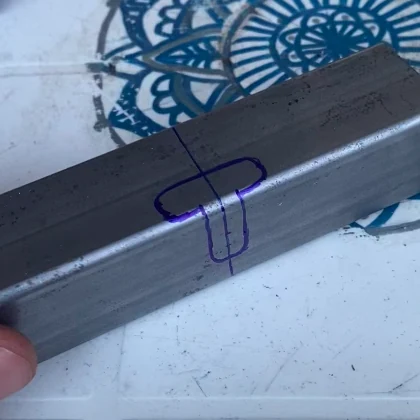 Perfil de acero rectangular con dibujo en forma de T con rotulador morado para adaptar en la furgoneta camper
