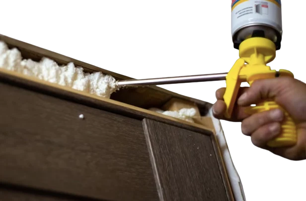 Mano usando espuma aislante para sellar huecos en la estructura de una furgoneta camper, mejorando el aislamiento