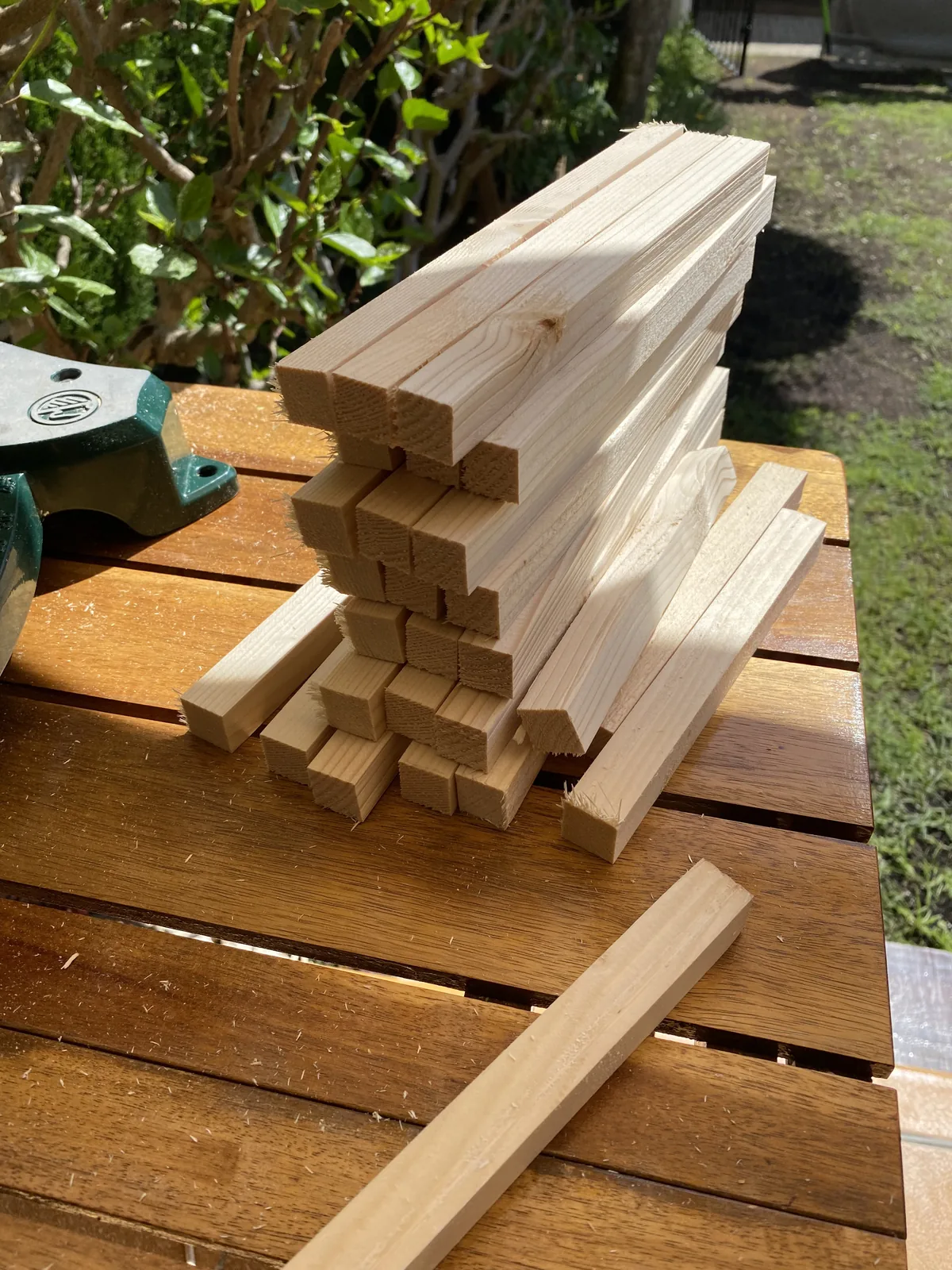 Listones de madera de pino recién cortados apilados en mesa de exterior junto a sargento, para mobiliario de furgoneta