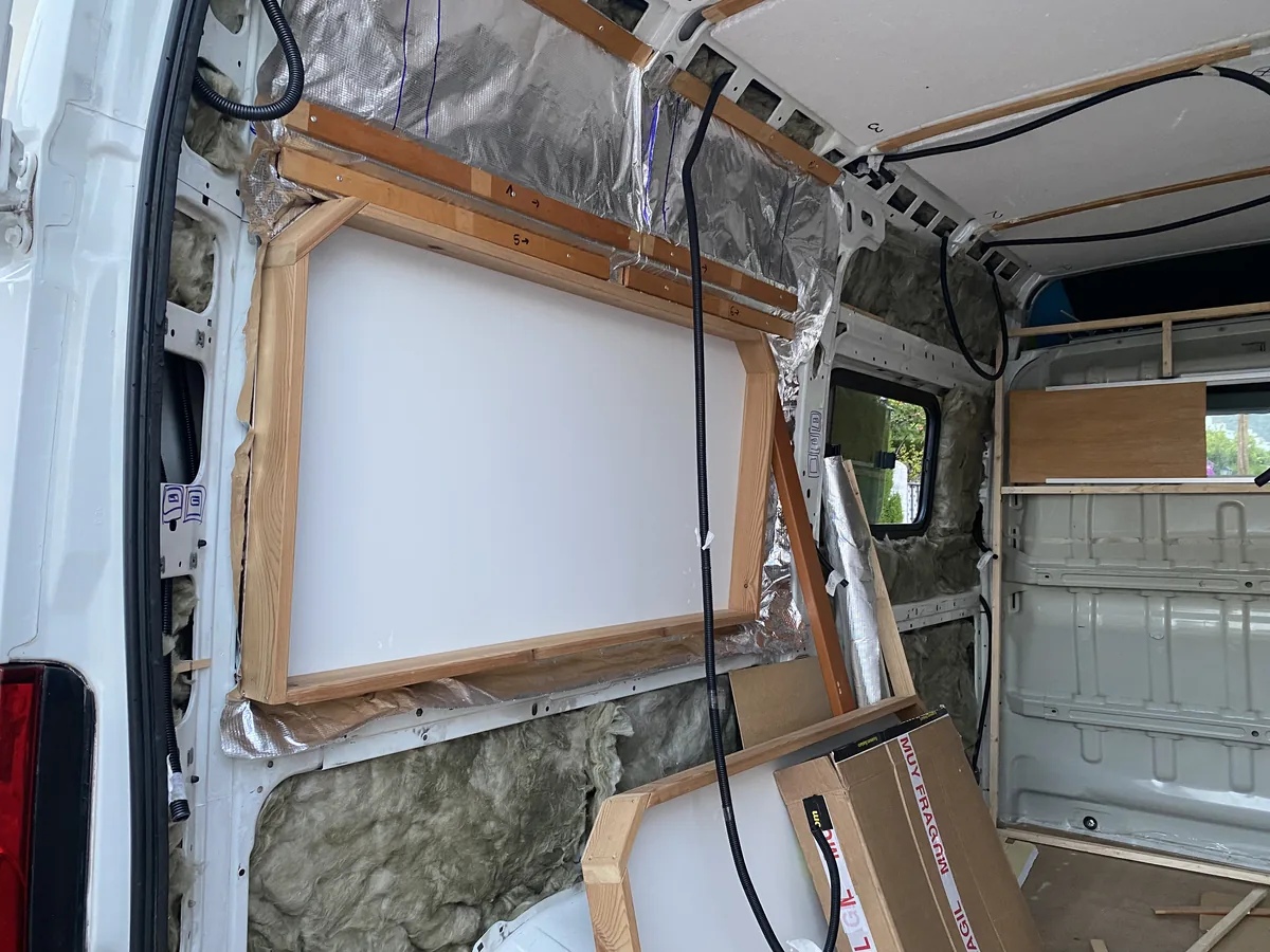 Interior de furgoneta camper en fase de construcción con aislamiento térmico y estructura de madera para el revestimiento
