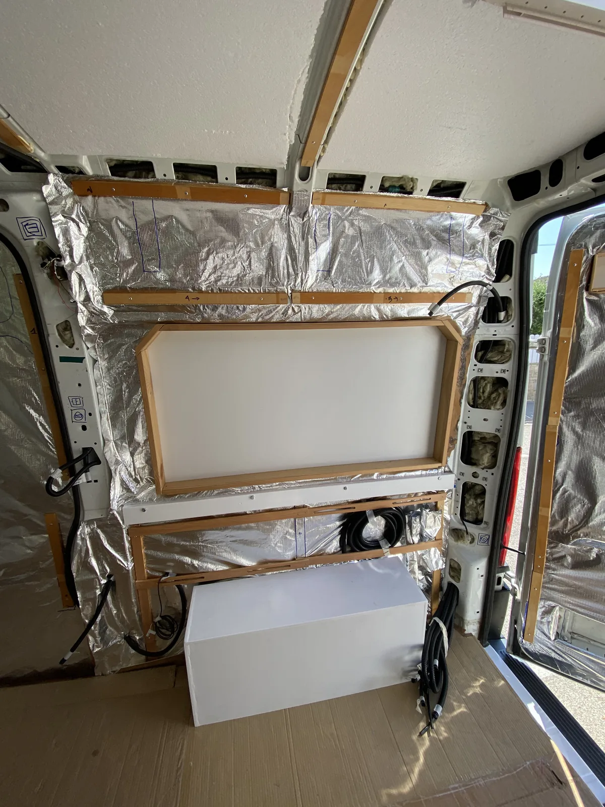 Interior de furgoneta camperizándose con aislamiento foil, listones de madera, un panel blanco y paso de rueda