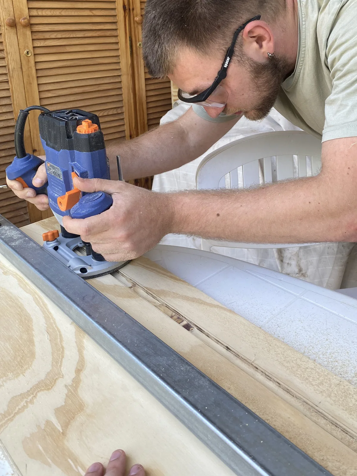 Un hombre usa una fresadora para hacer ranuras precisas en un panel de madera contrachapada para su furgoneta camper