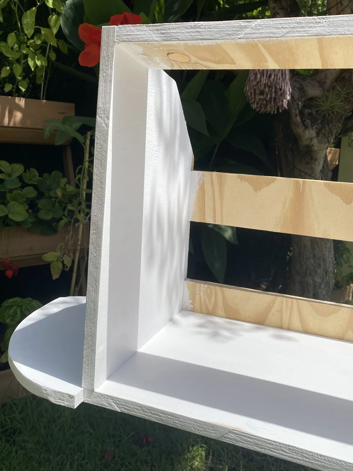 Estante de madera contrachapada para van camper, parcialmente pintado de blanco, siendo construido en un jardín
