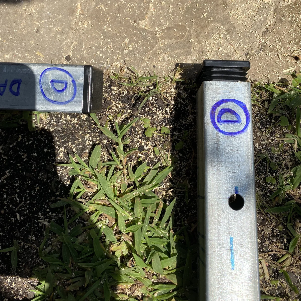 Perfiles metálicos cuadrados galvanizados con marcas azules y capuchón, listos para la construcción DIY de equipamiento