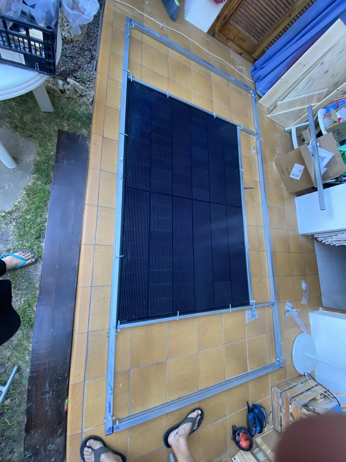 Gran panel solar para vehículo overland, con marco de aluminio, en proceso de montaje sobre baldosas