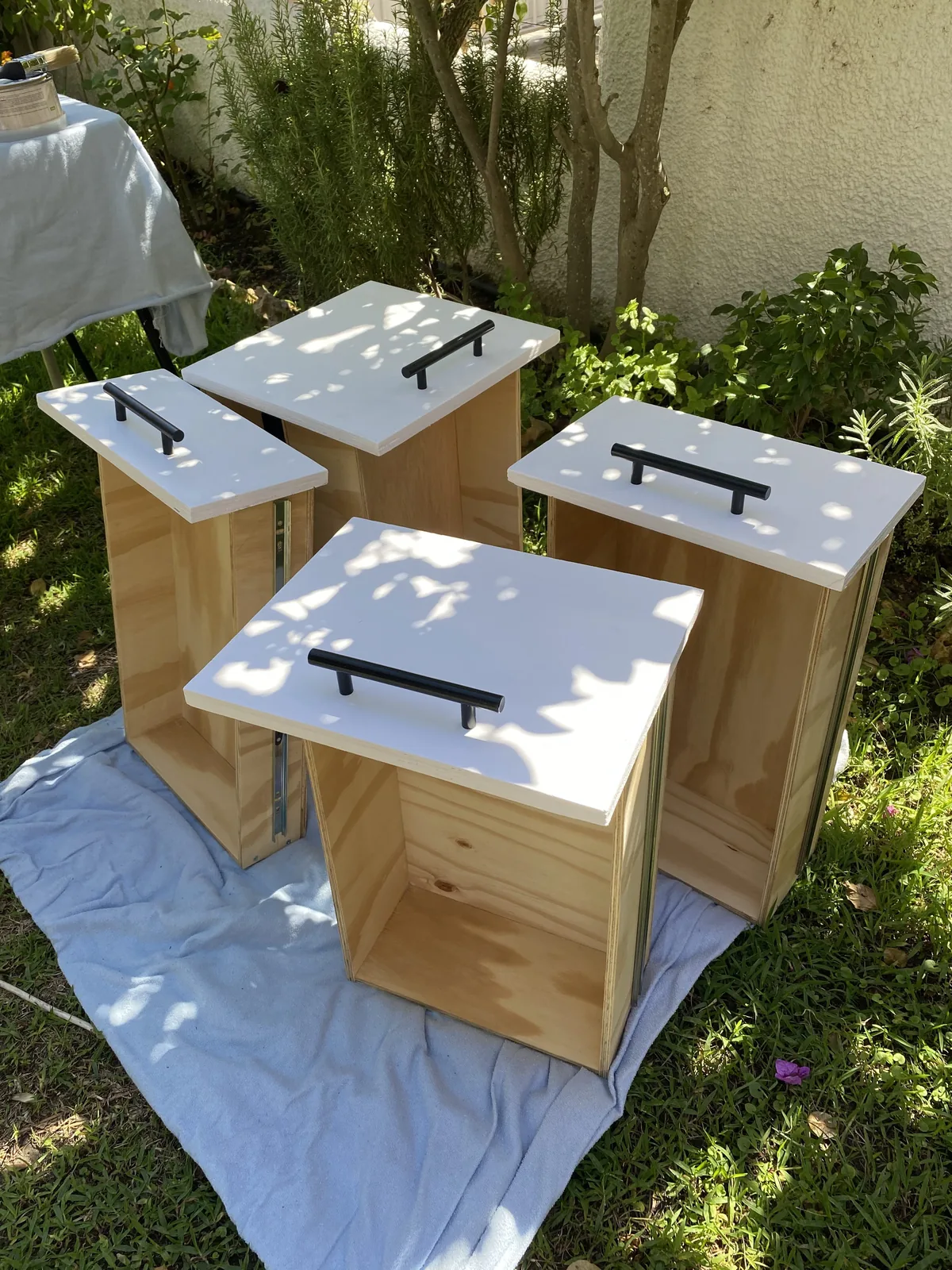 Cuatro cajones de madera DIY con tapas blancas y tiradores negros, diseñados para equipar una furgoneta camper overland