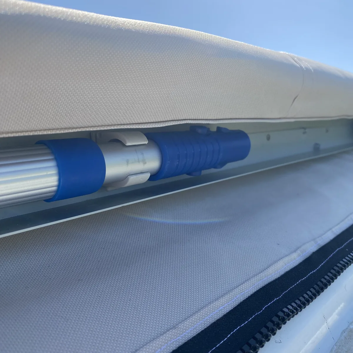 Varilla de toldo extensible azul y plata fijada bajo la lona protectora de una furgoneta camper para viajes overland
