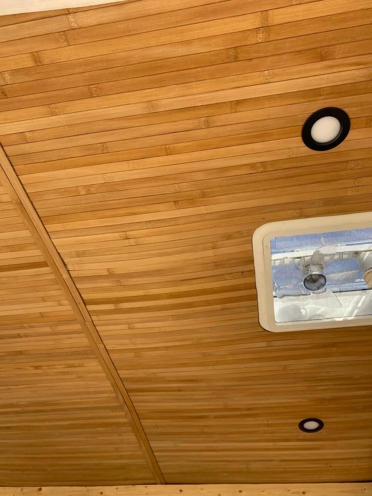 Techo de furgoneta overland revestido en bambú, con focos LED empotrados y claraboya para ventilación interior