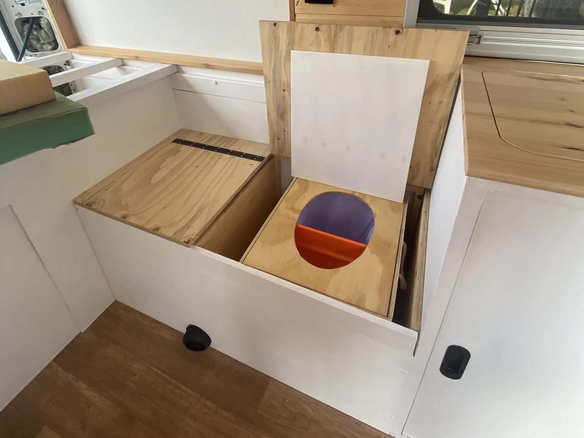 Inodoro separador de orina y sólidos, hecho con madera, integrado en los muebles de una furgoneta camper, ideal para viajes