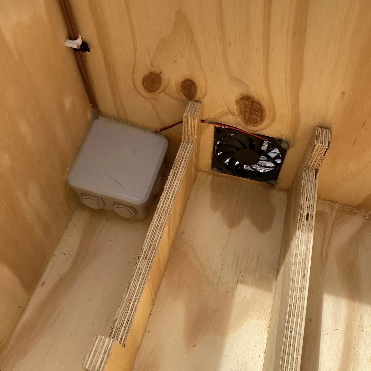 Caja de conexiones eléctrica y ventilador instalados en compartimento de madera de furgoneta camper overland