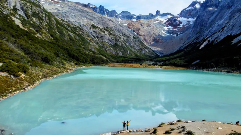 Aventureros en la orilla de Laguna Esmeralda, Ushuaia, disfrutando del lago turquesa y las montañas nevadas de Patagonia