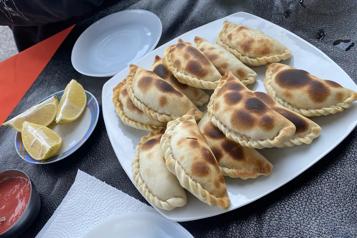Empanadas horneadas con el repulgue trenzado, acompañadas de limones y salsa, disfrutando la gastronomía de la ruta