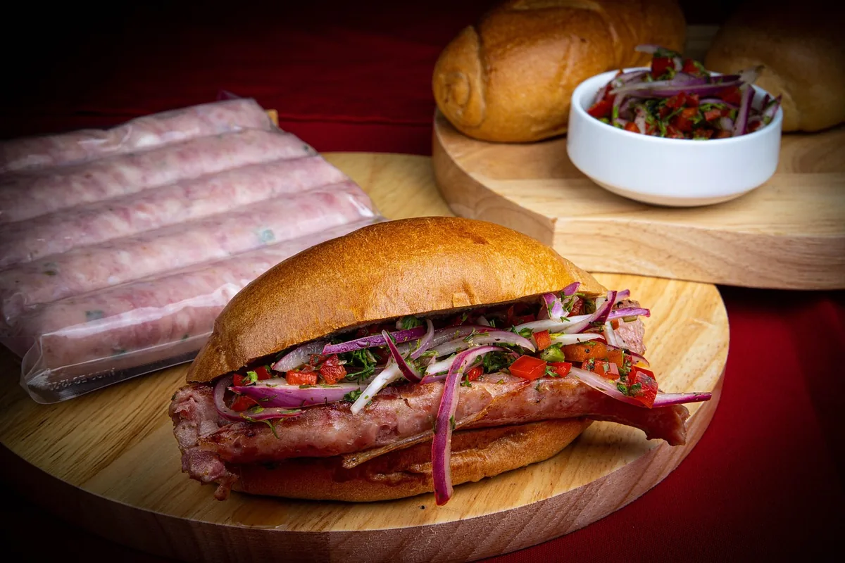 Choripán argentino con pebre fresco en pan, acompañado de salchichas, ideal para un viaje overland