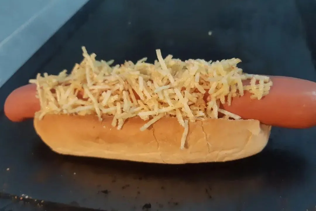 Perro caliente con salchicha, pan y una generosa capa de papas paja, una opción de comida rápida para ruta overland