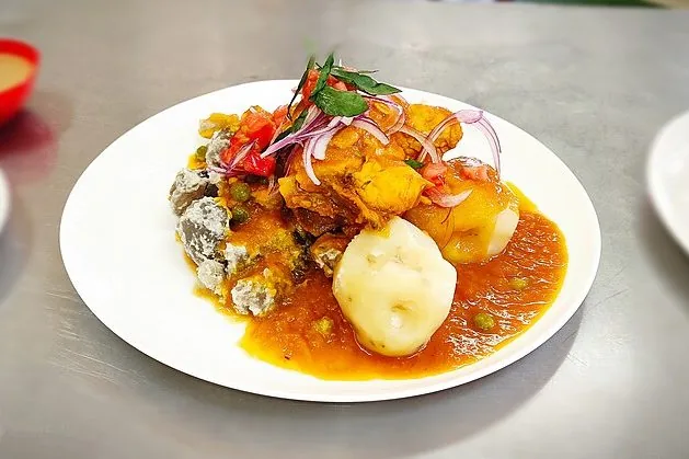 Delicioso plato con pollo en salsa, papas andinas y guisantes, coronado con cebolla morada. Comida típica en ruta
