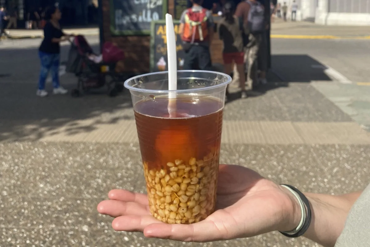 Mano sostiene vaso de mote con huesillo, bebida tradicional de Chile con granos de trigo, en un mercado callejero