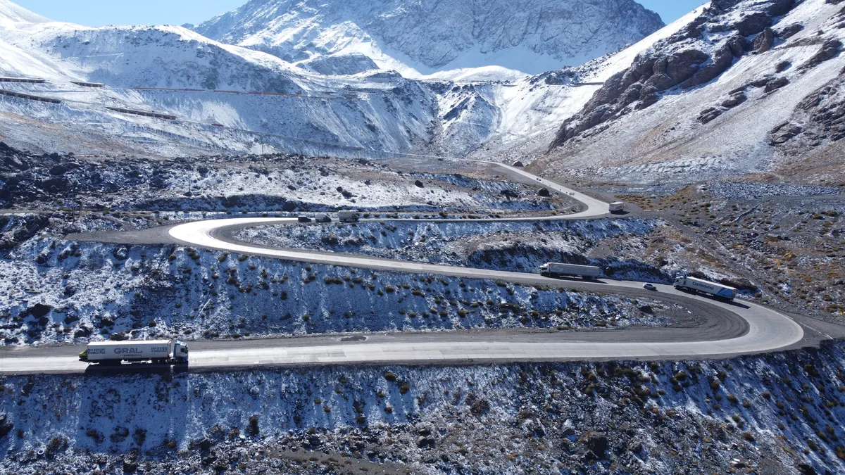 Carretera de los Caracoles nevada en el Paso Los Libertadores, Andes, con camiones en las curvas