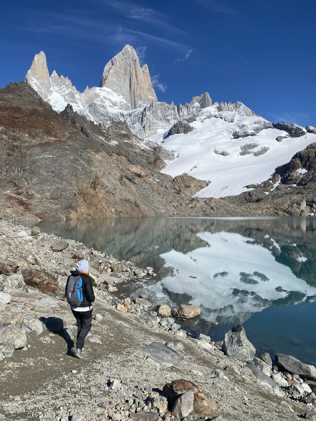 Viajera con mochila observa el majestuoso Monte Fitz Roy y su reflejo en la Laguna de los Tres, El Chaltén, Argentina