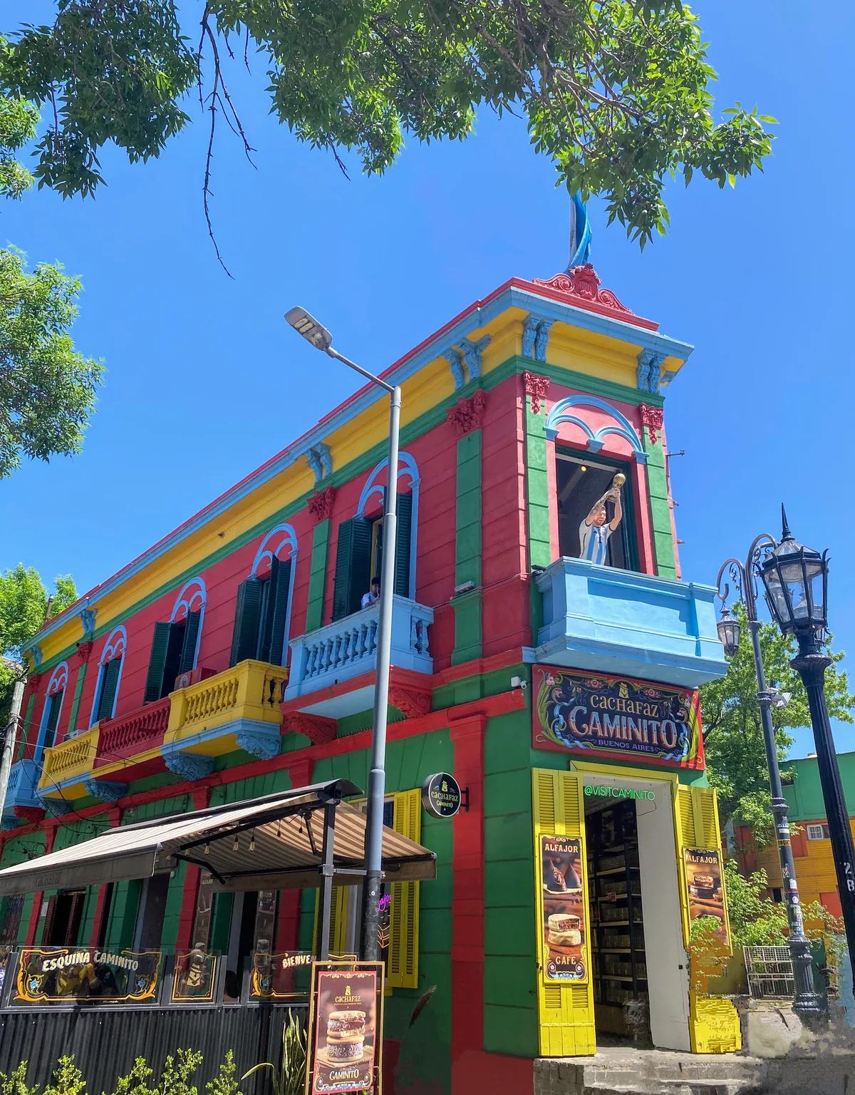 Vibrante edificio multicolor de Caminito en La Boca, Buenos Aires, con un hincha argentino celebrando en el balcón