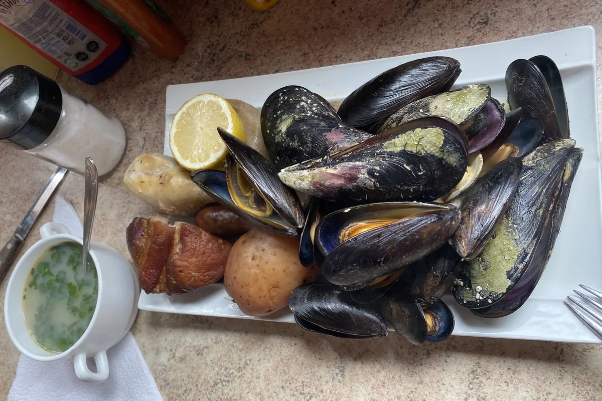 Mejillones frescos con patatas, embutidos y carne ahumada, acompañados de limón y sopa, comida camper en ruta