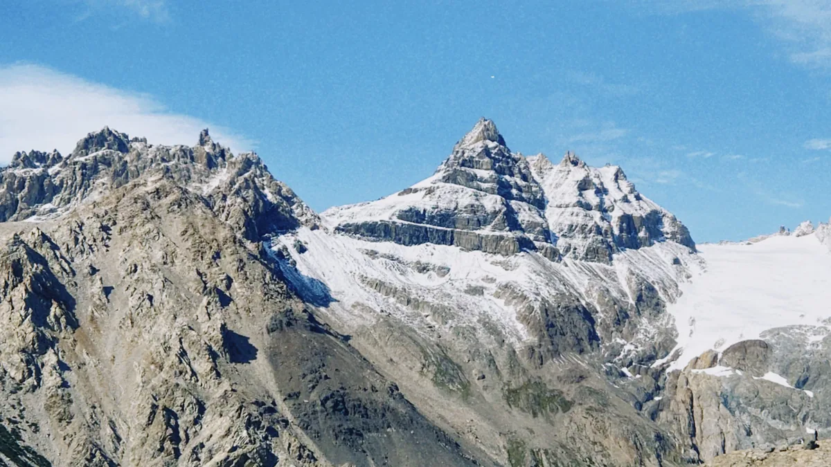 Imponente cordillera con picos rocosos nevados y glaciares bajo un cielo azul vibrante