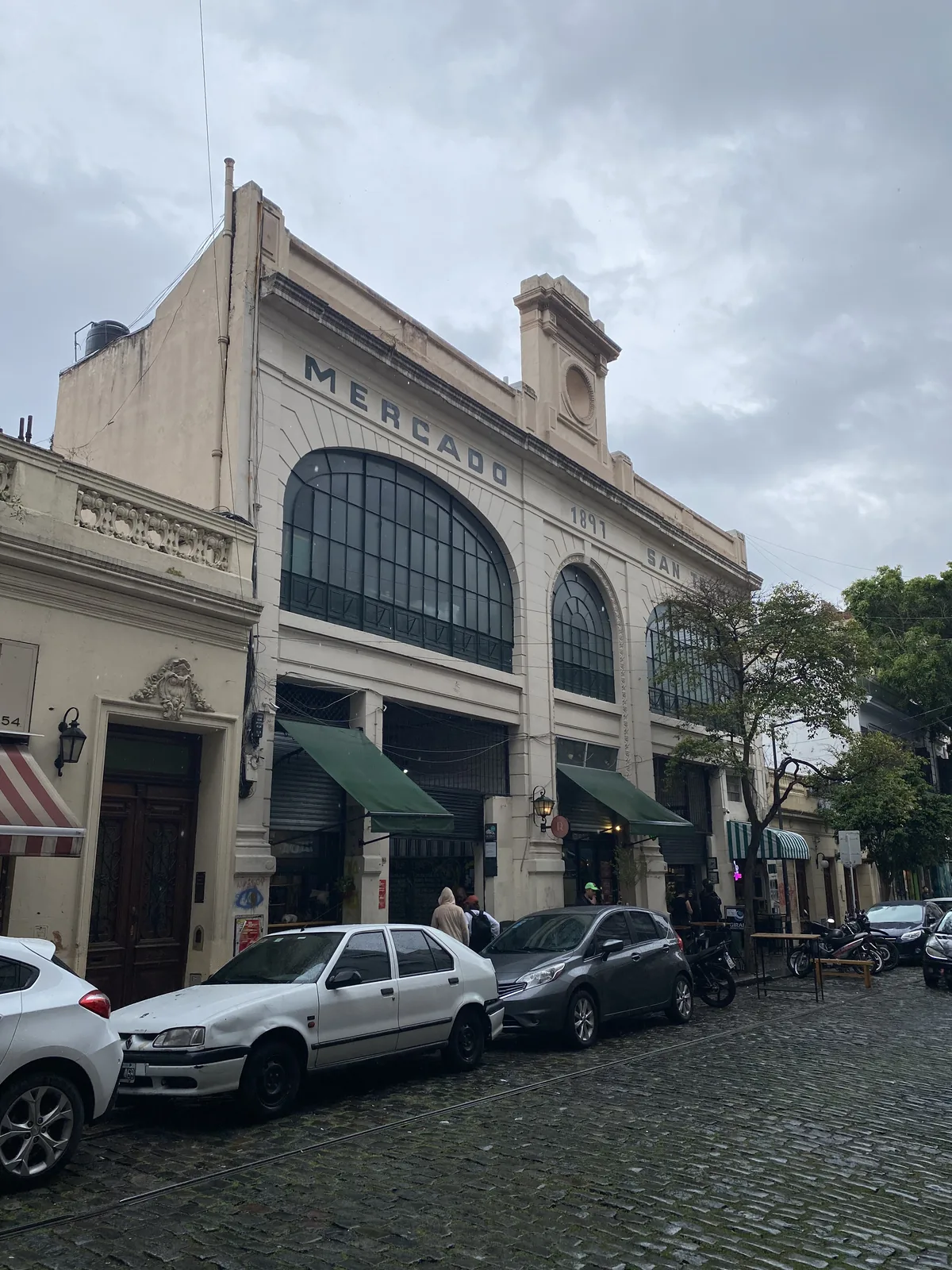 Mercado de San Telmo en Buenos Aires, Argentina, con su histórica fachada de 1897 y calle adoquinada bajo cielo nublado