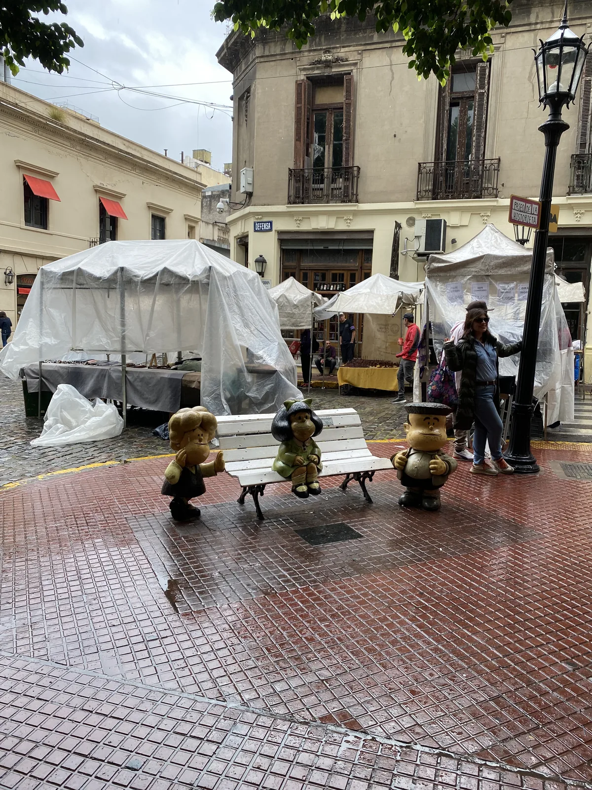 Figuras de Mafalda, Manolito y Felipe en el Paseo de la Historieta de San Telmo, Buenos Aires, entre puestos de feria