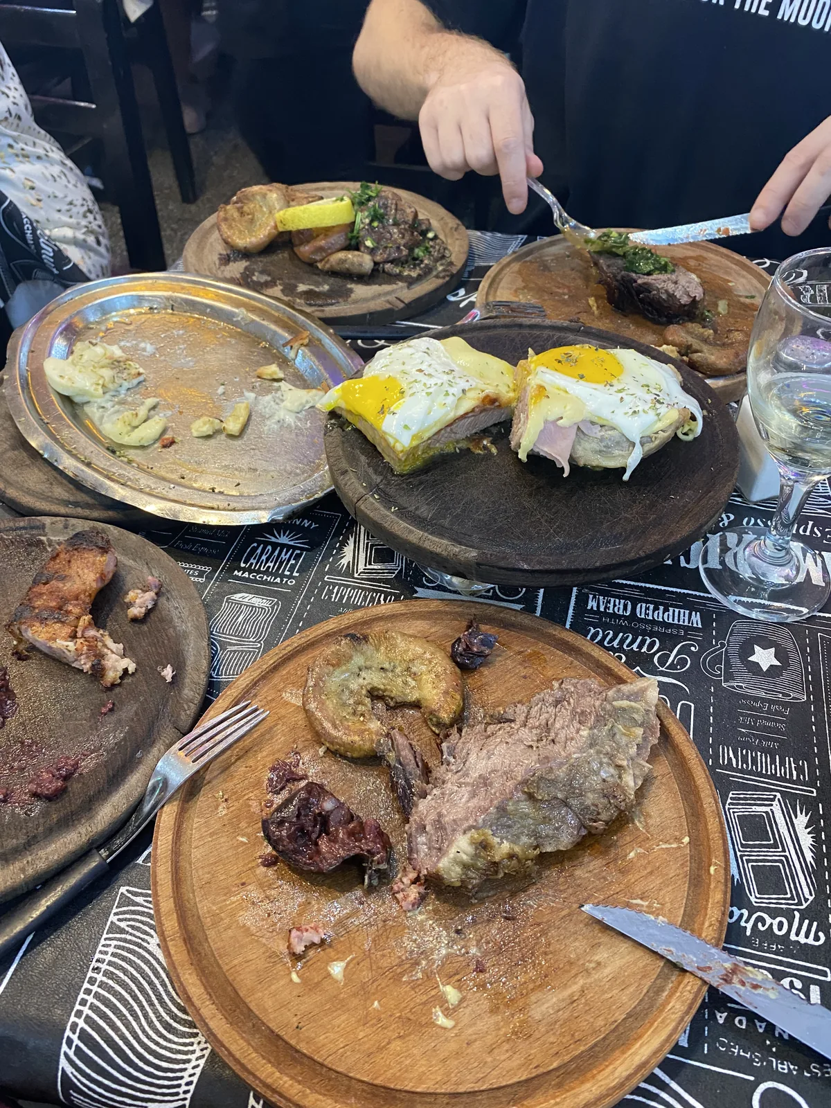 Gastronomía argentina en un restaurante: asado, morcilla, chinchulines y milanesas a caballo en tablas de madera