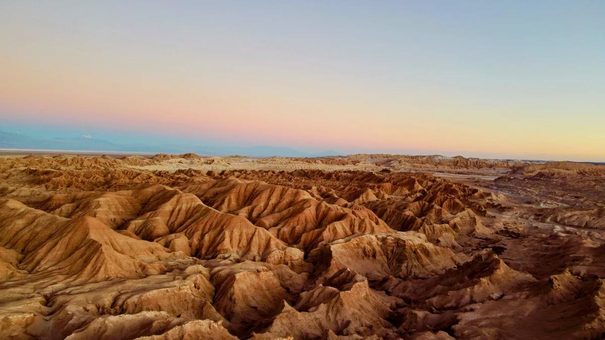 Atardecer en el Valle de la Luna, desierto de Atacama, Chile. Montañas erosionadas bajo cielo rosado y azul
