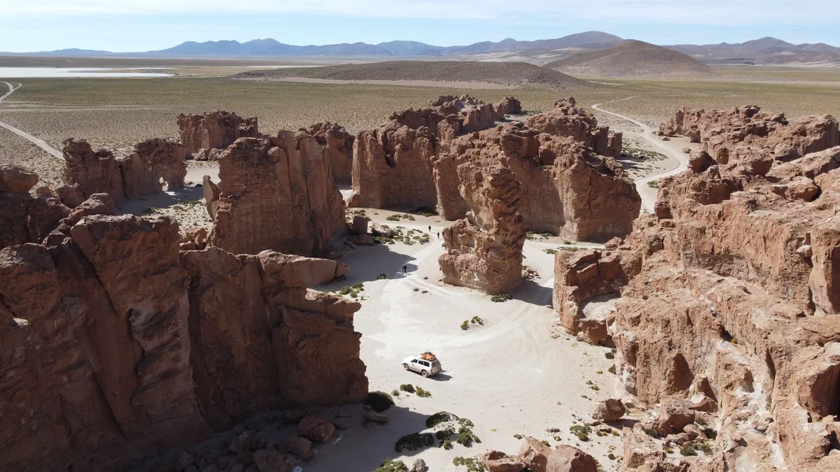 4x4 overland blanco estacionado entre formaciones rocosas gigantes del Valle de Rocas en el altiplano boliviano