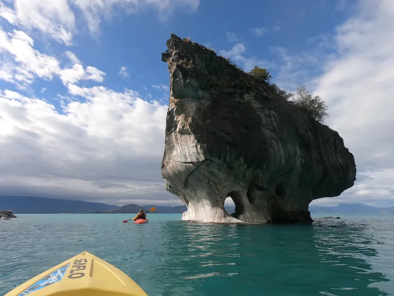 Kayakista explorando las Capillas de Mármol en Lago General Carrera, Patagonia chilena, aguas turquesas y cielo nublado
