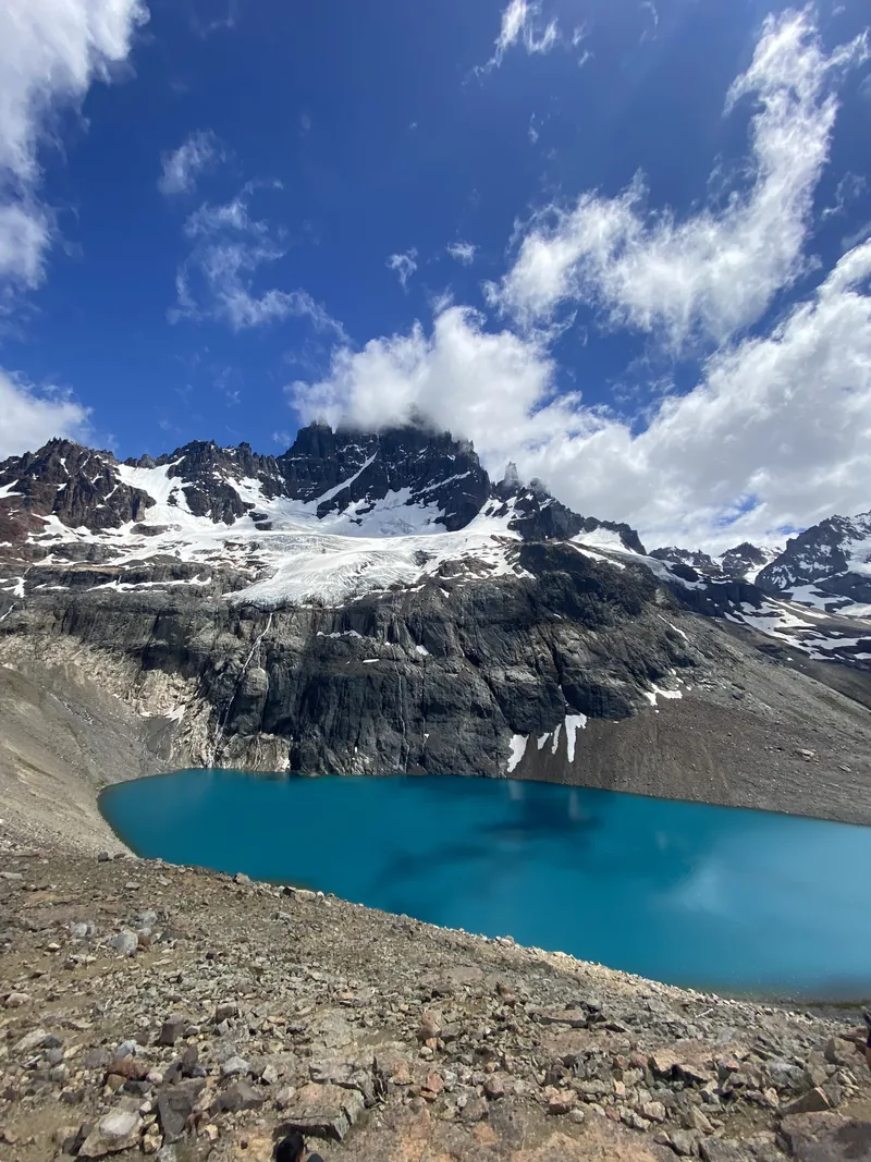 Lago turquesa de origen glaciar con imponentes montañas nevadas y picos rocosos, típico paisaje de la Patagonia