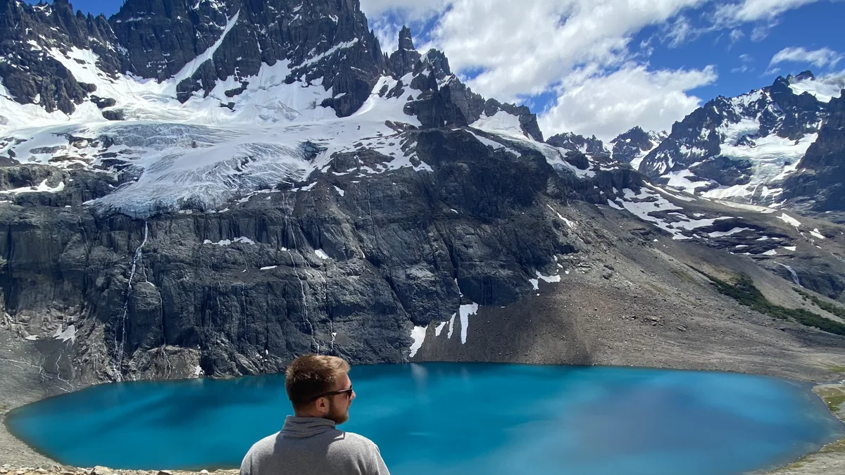Hombre contemplando un impresionante lago glaciar turquesa entre picos nevados y glaciares en Patagonia