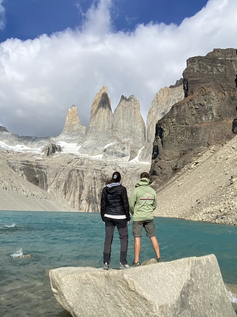 Pareja admira las Torres del Paine y lago turquesa glaciar en Patagonia, Chile. Un destino overland imperdible