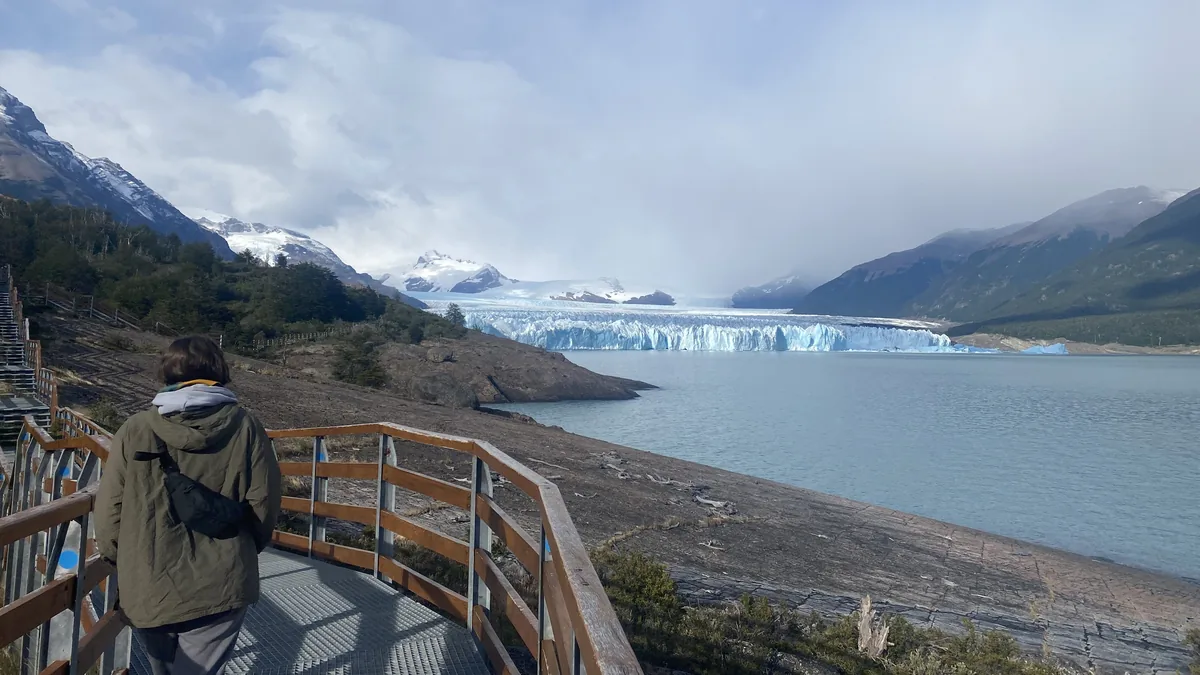 Viajero en pasarela viendo el Glaciar Perito Moreno y el Lago Argentino, rodeado de montañas nevadas en Patagonia