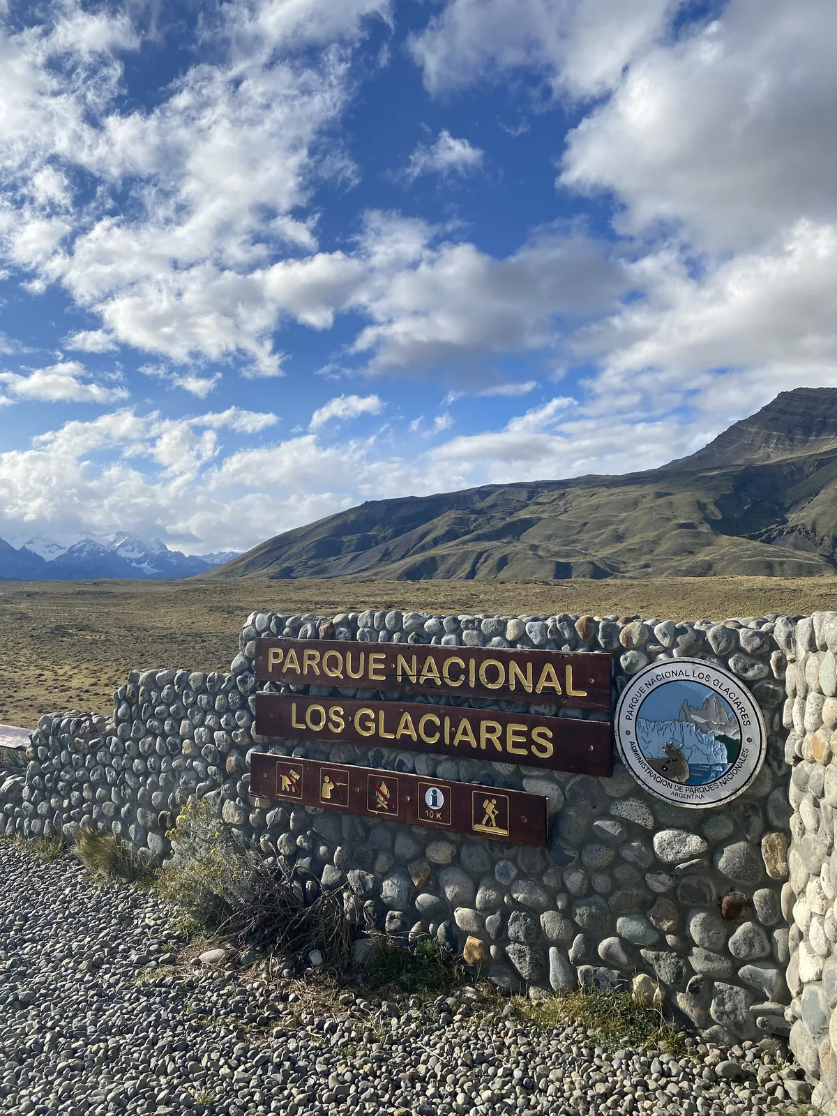 Entrada de piedra al Parque Nacional Los Glaciares, Patagonia, con montañas nevadas y vasto paisaje árido bajo cielo azul