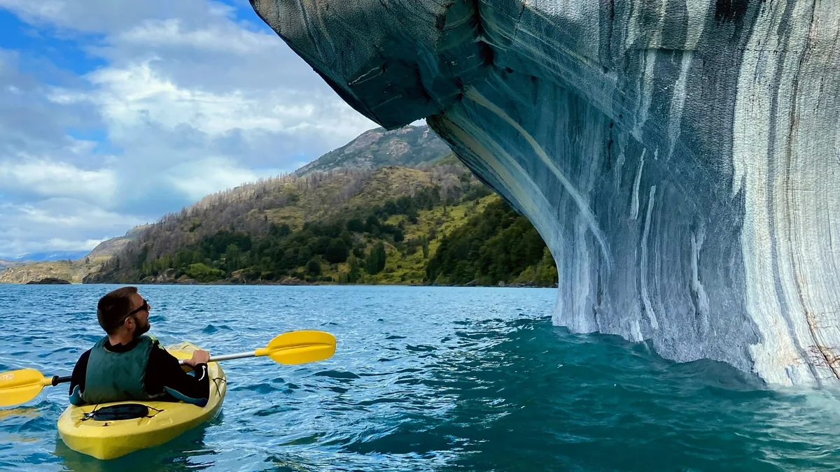 Hombre en kayak amarillo explorando las Capillas de Mármol en Lago General Carrera, Patagonia chilena