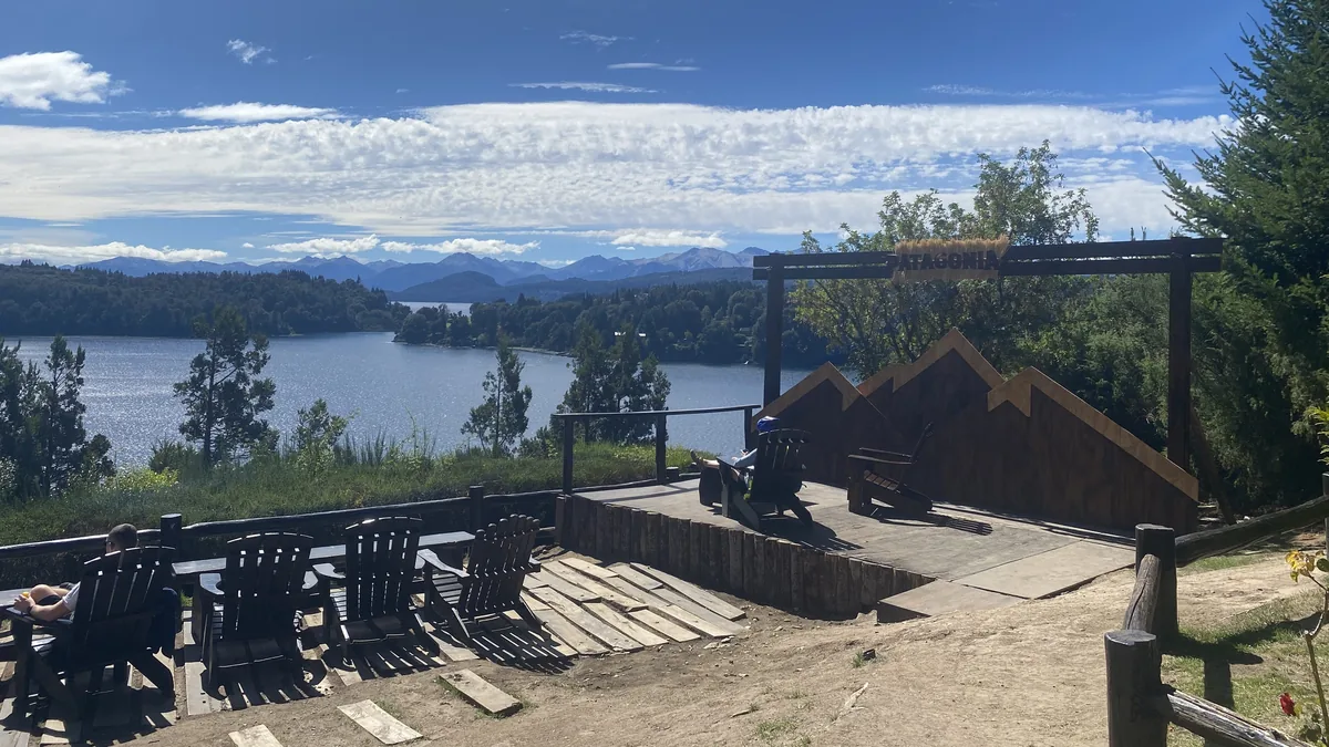Mirador PATAGONIA con sillas de madera y vista espectacular de un lago, frondosos bosques y montañas bajo cielo azul
