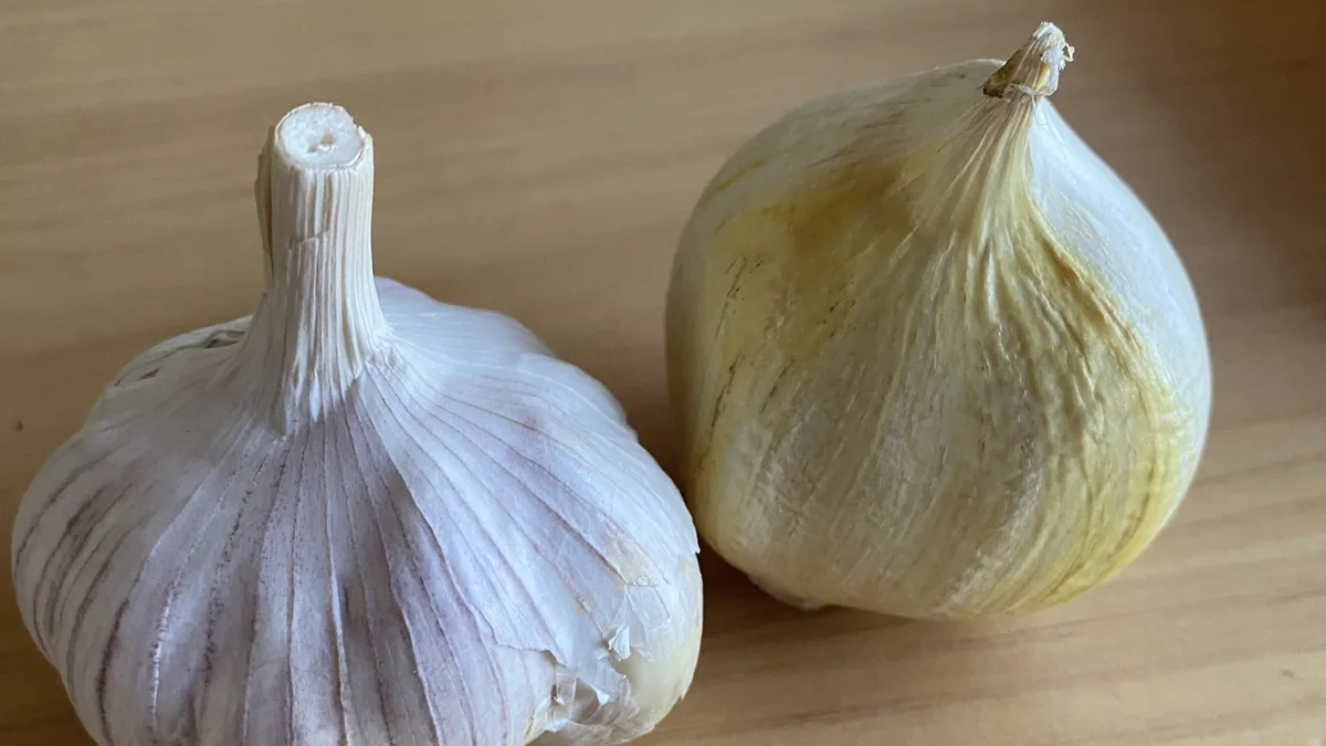 Dos cabezas de ajo frescas sobre una tabla de madera, ingredientes esenciales para cocinar en ruta