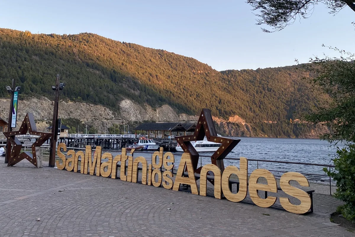 Cartel de San Martín de los Andes junto al Lago Lácar y montañas, atardecer en Patagonia argentina, destino overland