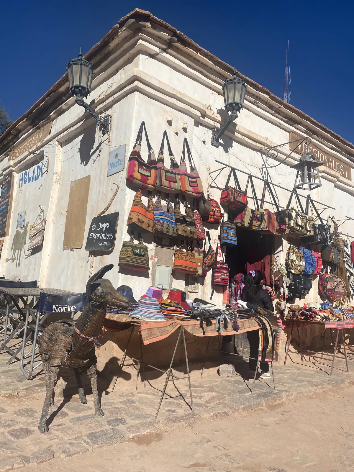 Artesanías regionales con coloridos bolsos tejidos y sombreros en un puesto callejero en Tilcara, Jujuy