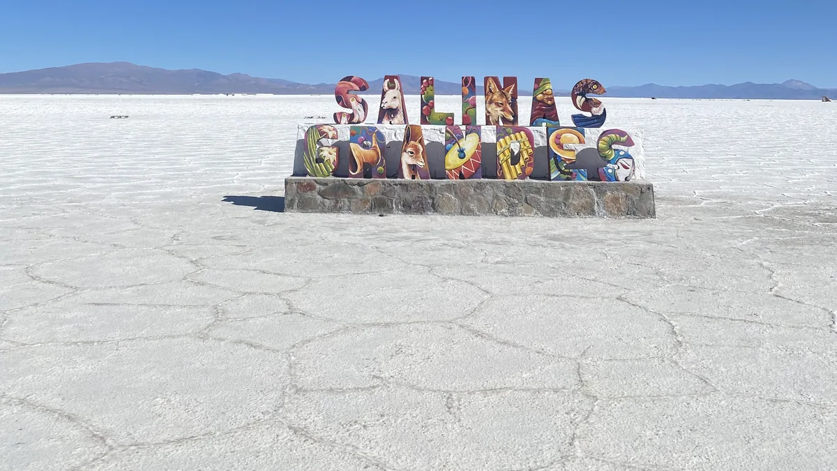Señal de Salinas Grandes con arte andino en el salar de Jujuy. Paisaje vasto para aventura overland