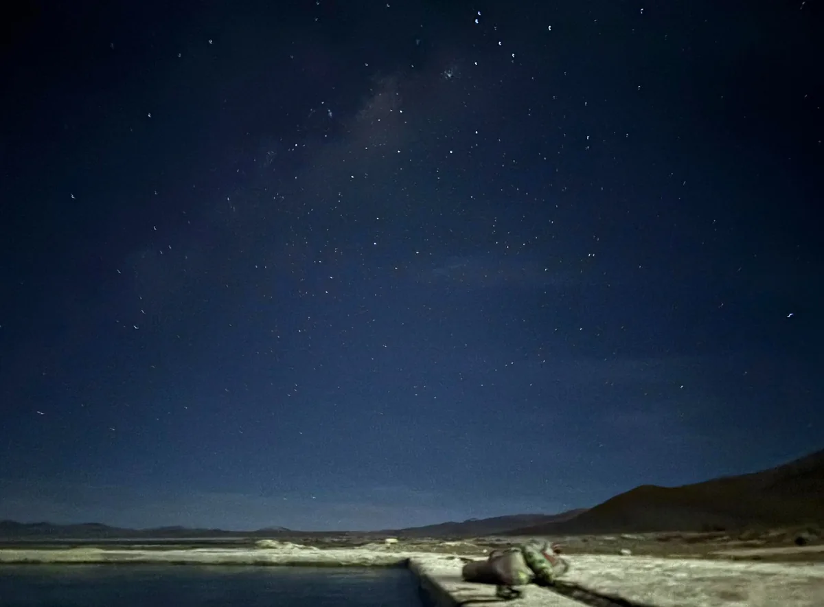 Noche estrellada en el desierto, con sandalias junto a una poza de aguas termales, un respiro ideal para viajeros overland