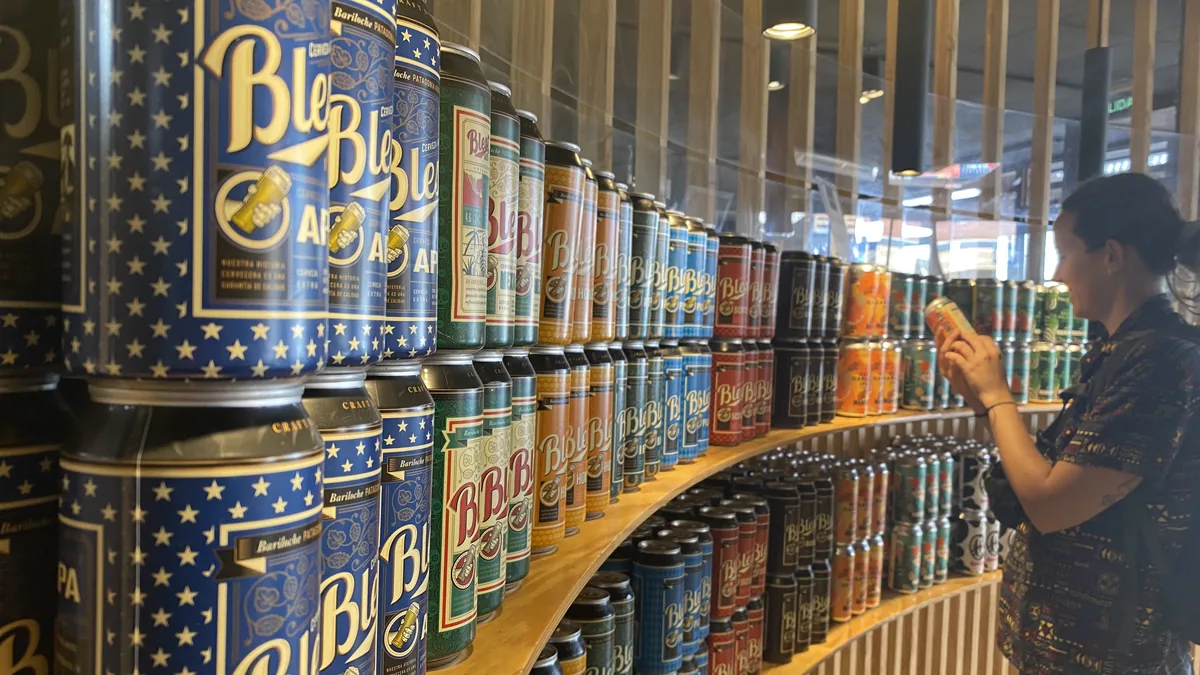 Mujer observando latas de cerveza artesanal Blef de Bariloche Patagonia en una estantería de exposición
