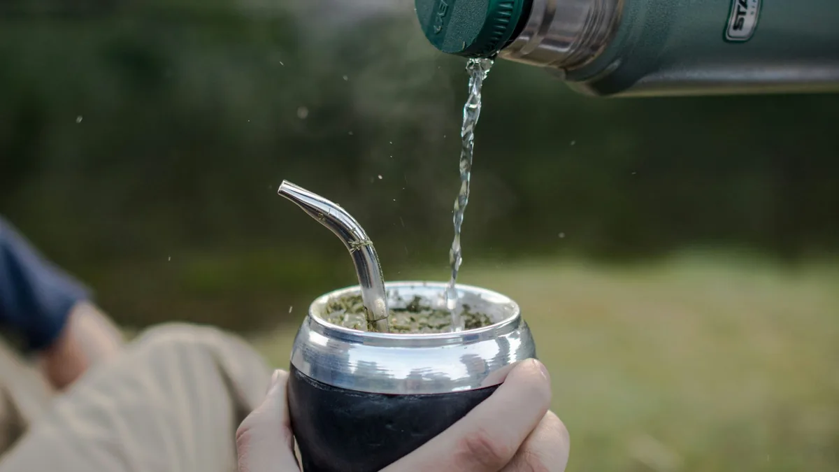 Primer plano de mate recién cebado con termo Stanley en mano, disfrutando la rutina en un viaje overland