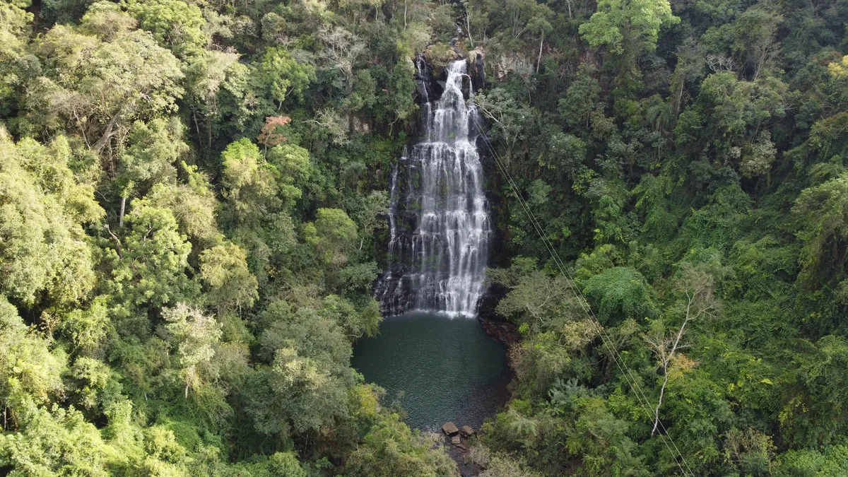 Espectacular cascada de múltiples caídas en medio de una densa selva tropical, con una poza verde esmeralda al pie