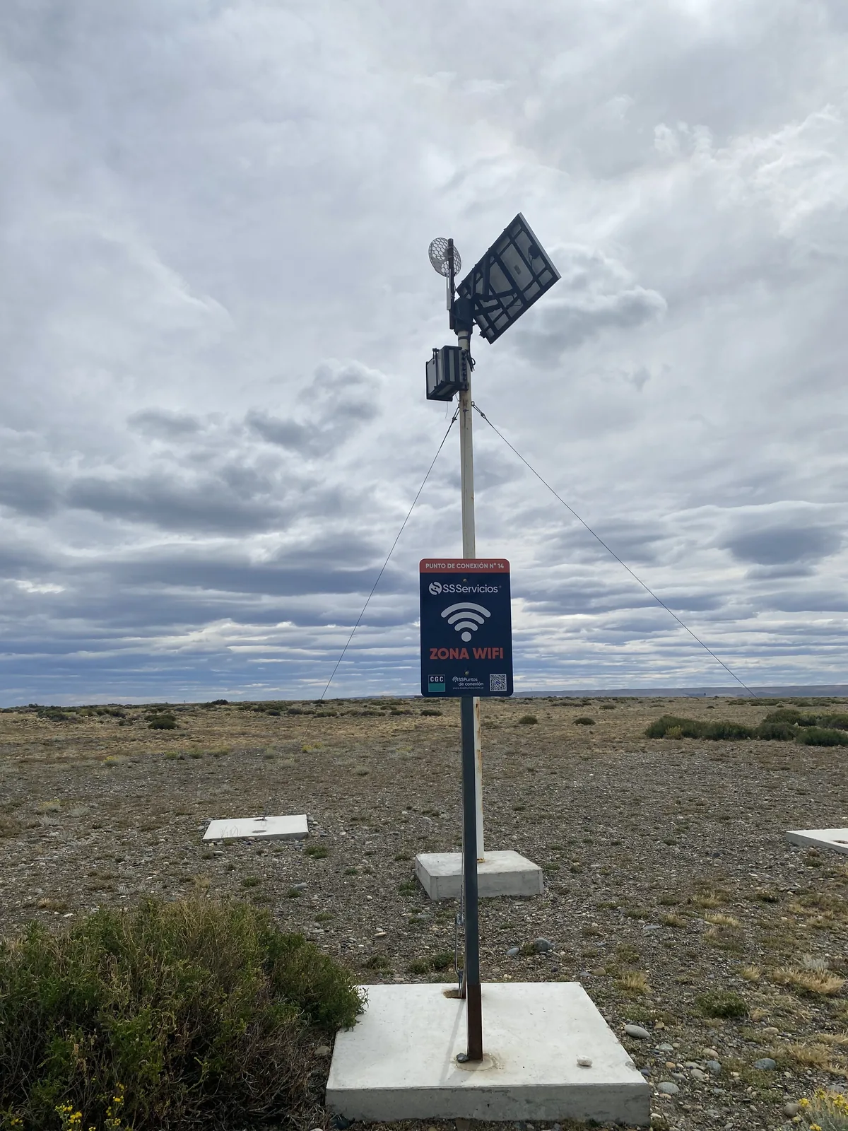 Poste con señal de Zona WiFi, panel solar y antena en paisaje árido, perfecto para overlanders