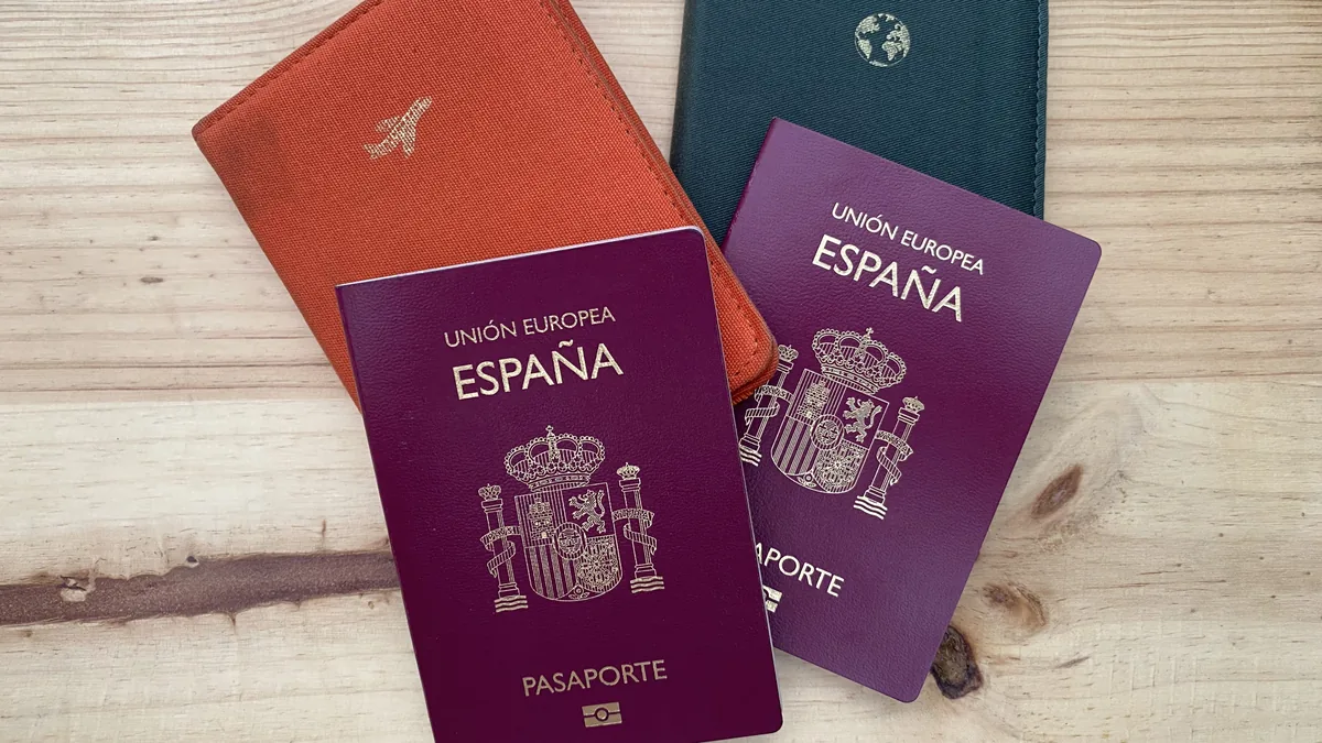 Pasaportes españoles y fundas de viaje sobre madera clara, preparativos esenciales para una aventura o ruta overland