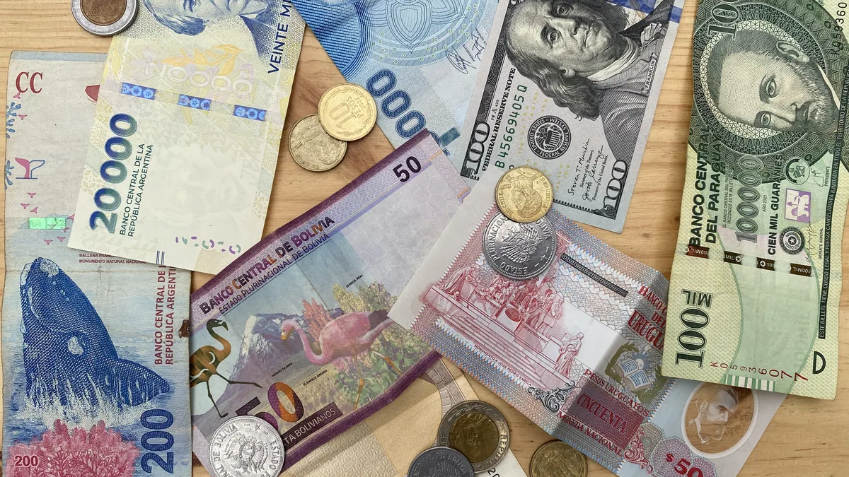 Billetes y monedas de Argentina, Bolivia, Paraguay, Uruguay y dólares de EE.UU. en una superficie de madera
